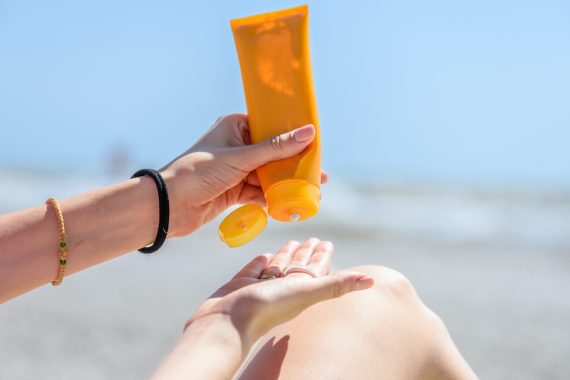 A woman holding bottles of sunscreen in her hands.